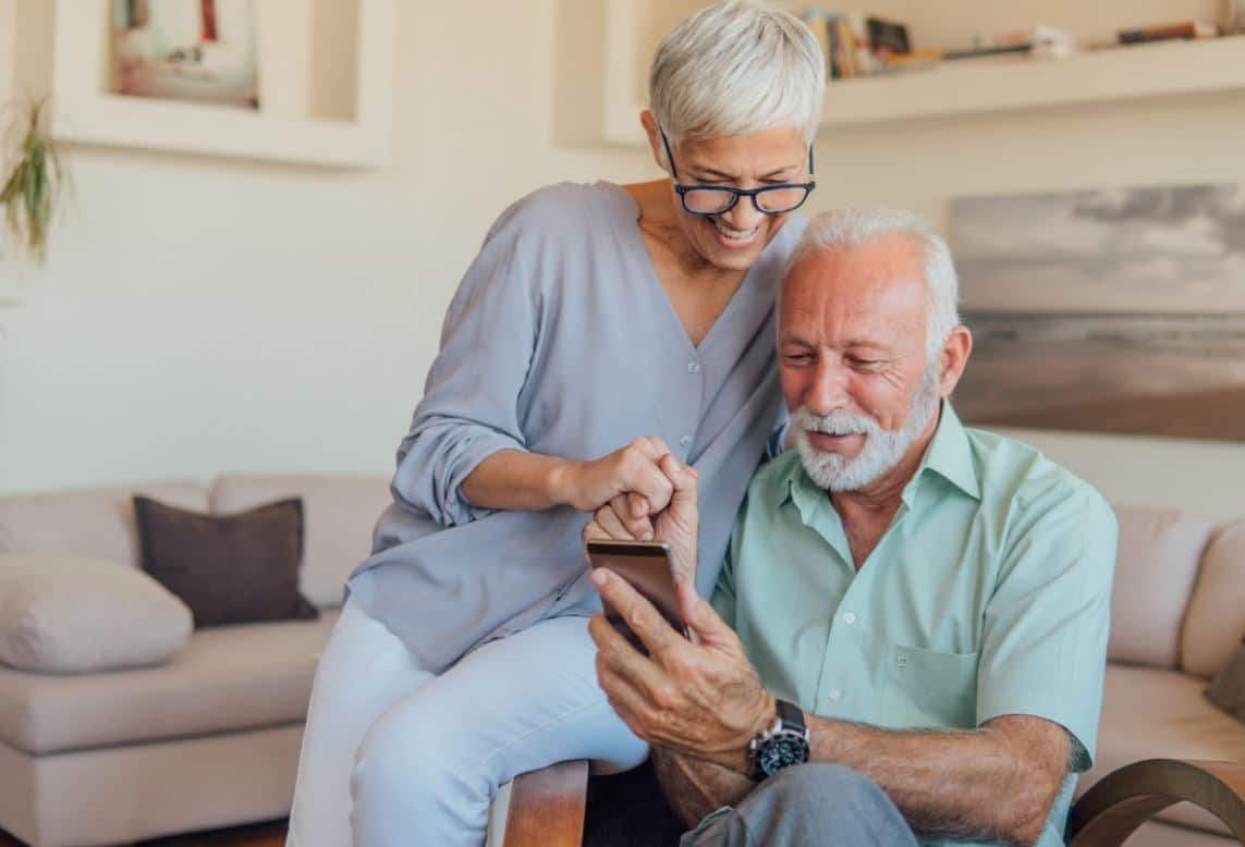 Couple senior utilisant le téléphone pour se connecter en ligne