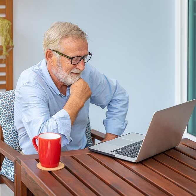 Homme senior utilisant un ordinateur portable sur une terrasse